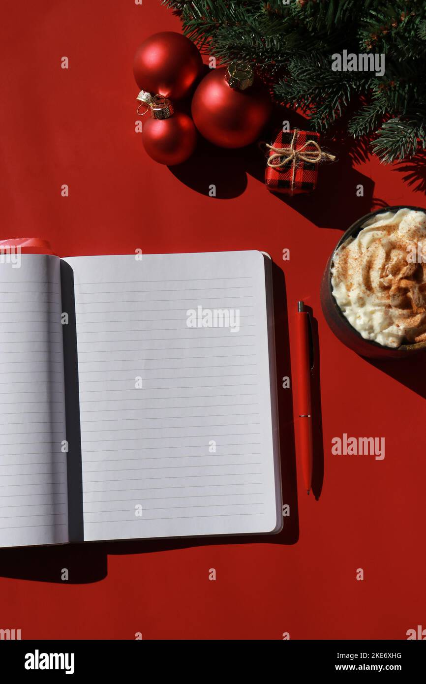 Rote Weihnachtskomposition mit heißer Schokolade und Notizbuch für Wunschliste Stockfoto