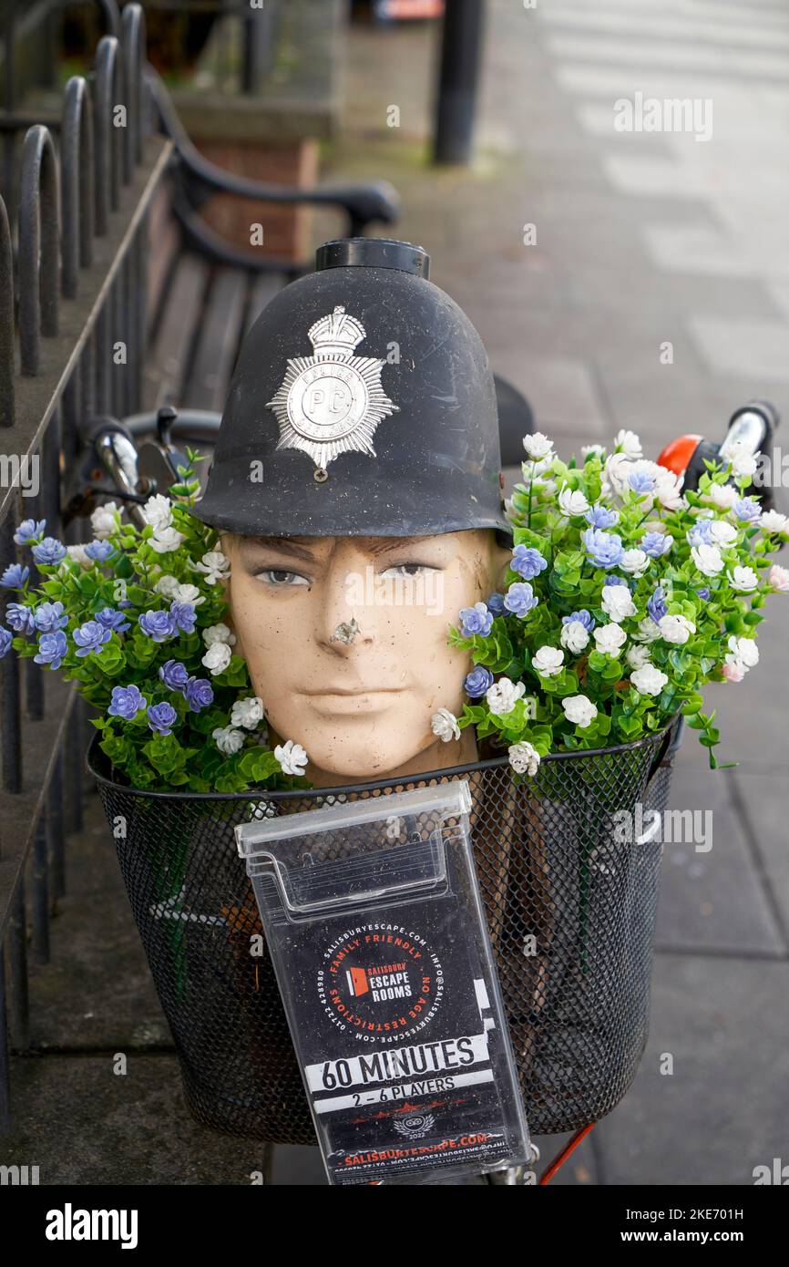 Dummy-Kopf trägt einen Polizist Helm in einem Korb auf einem Fahrrad mit Blumen Werbung für ein lokales Unternehmen Stockfoto