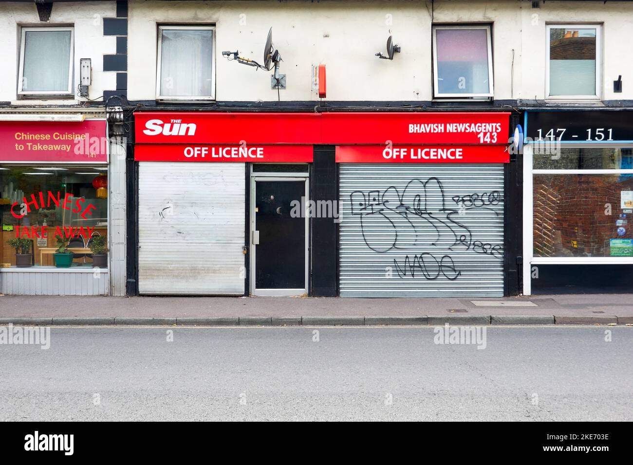 Sicherheitsläden aus Stahl, die die Fenster eines Zeitungskiosks und eines Lizenzladens mit Graffiti bedecken Stockfoto