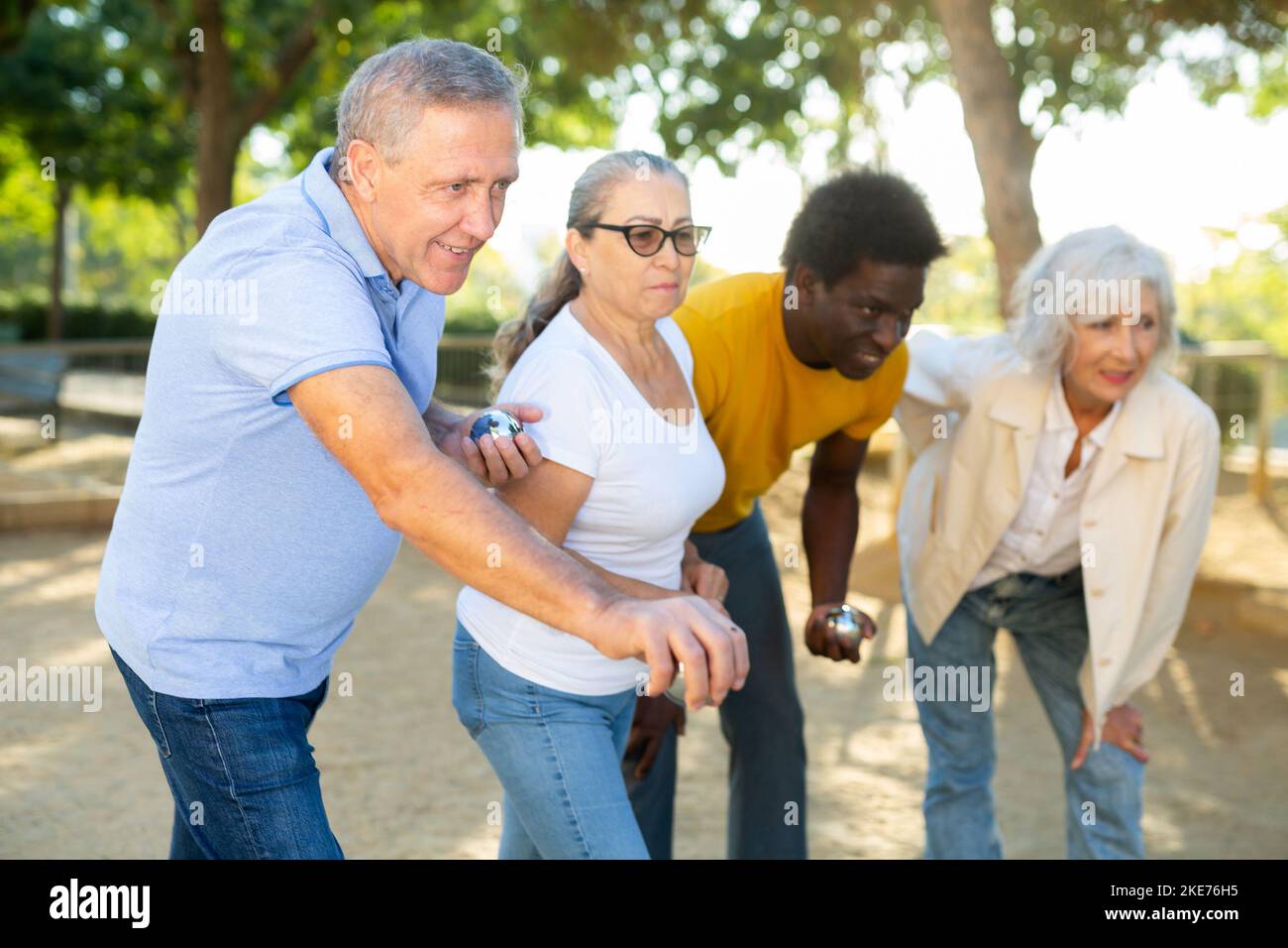 Eine Gruppe von multirassischen erwachsenen Menschen, die im Freien in einem Park patanque spielen Stockfoto