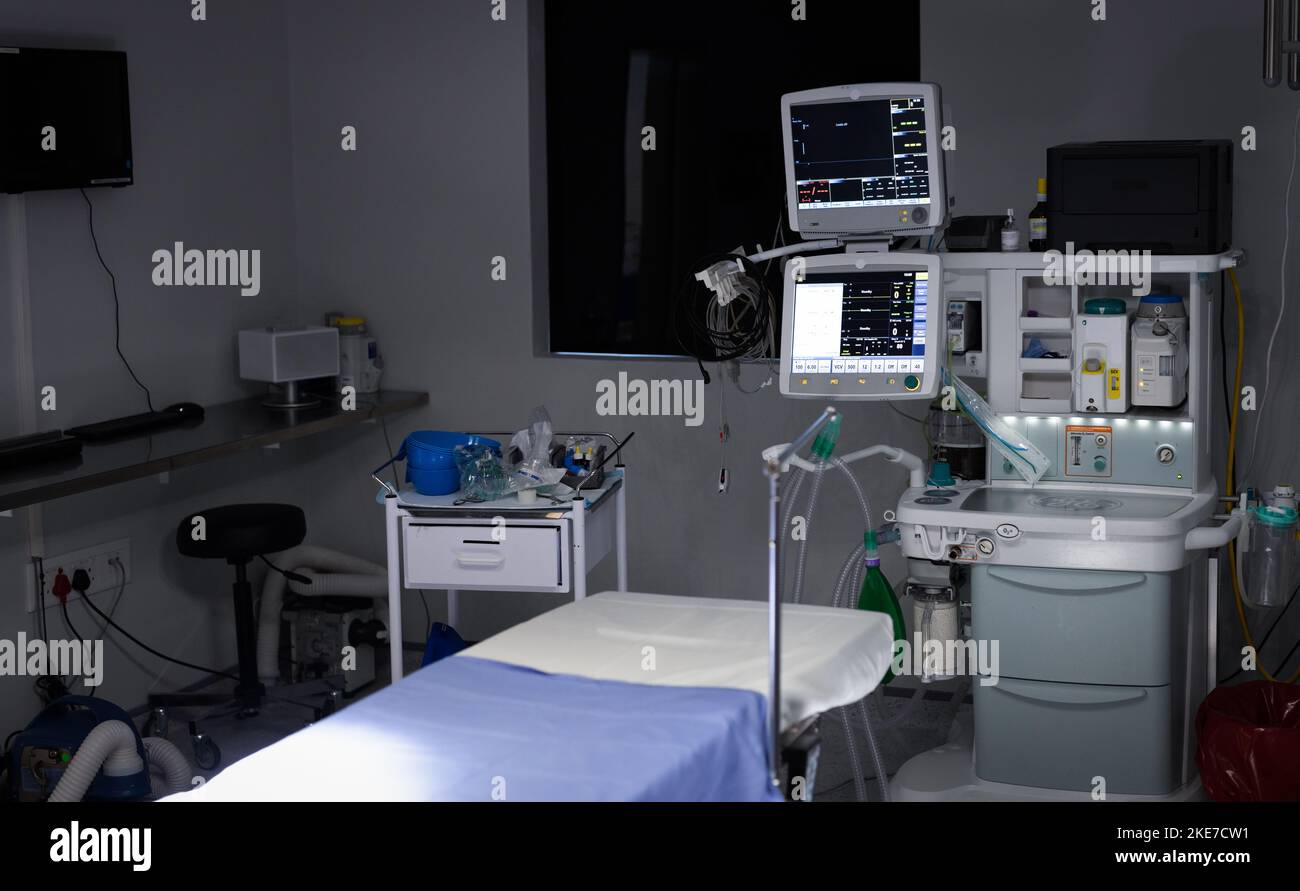 Elektronische medizinische Geräte mit Monitorbildschirmen und leerem Operationstisch im Operationssaal Stockfoto