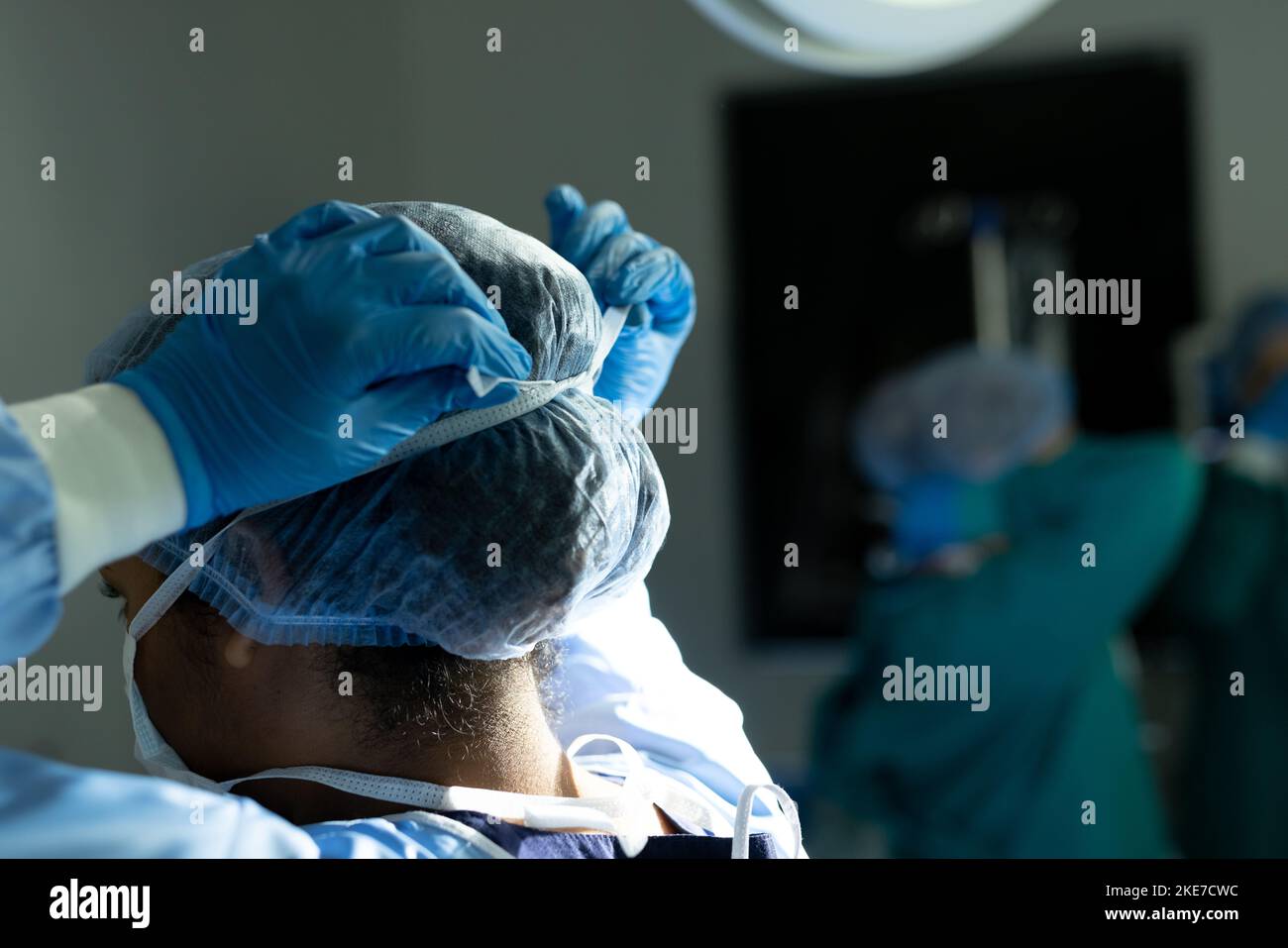 Rückansicht einer birassischen Chirurgin in Handschuhen und Kapselbindemaske im Theater, mit Kopierraum Stockfoto