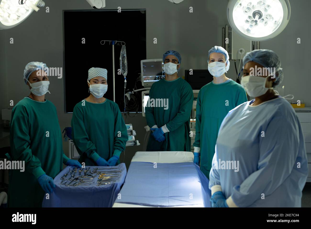 Ein vielseitiges Team von Chirurgen und Technikern, bereit für die Operation, steht im Operationssaal um den Operationstisch Stockfoto