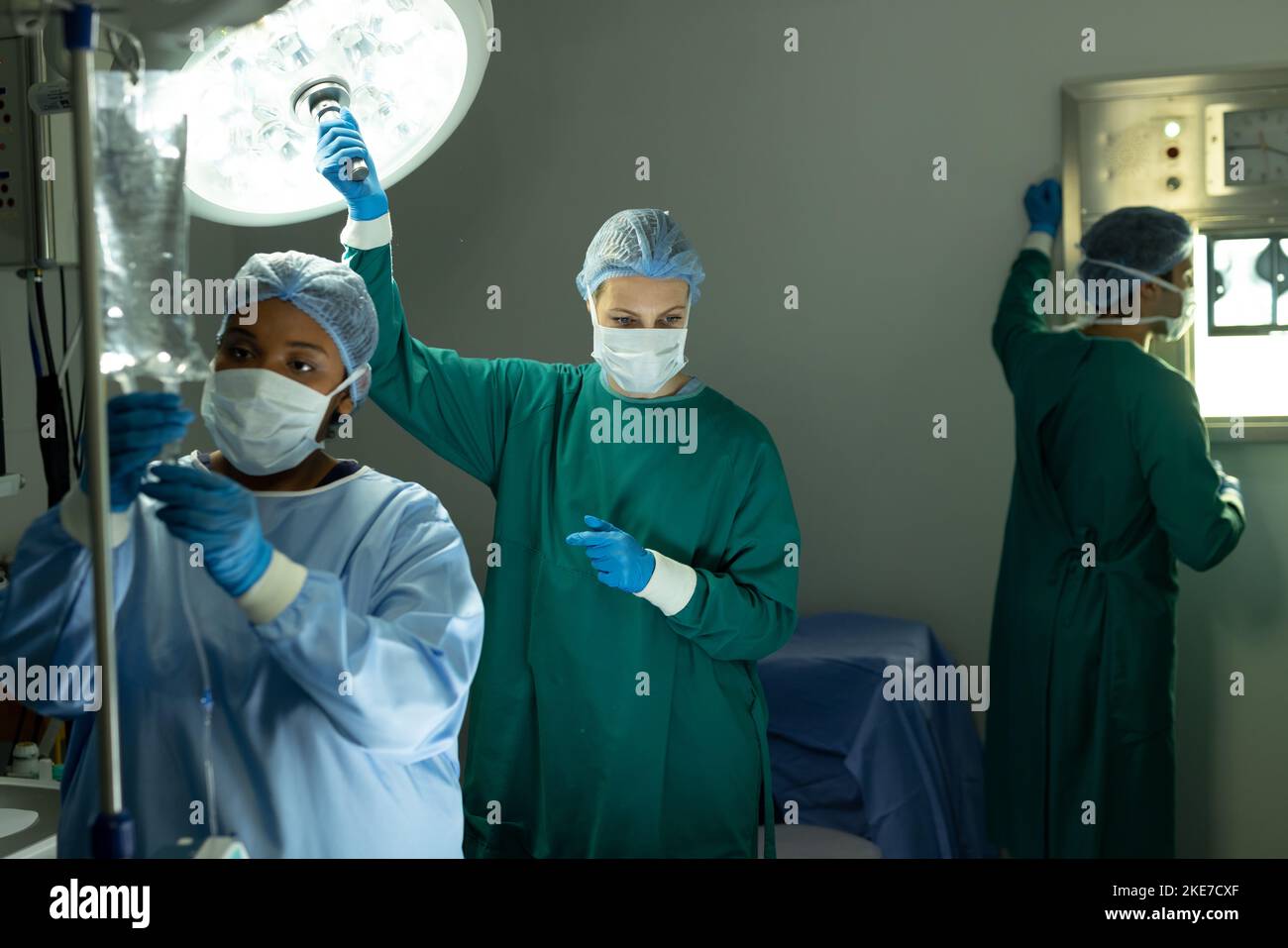 Zwei verschiedene Chirurgietechniker passen Licht und iv-Tasche im Operationssaal während der Operation an Stockfoto