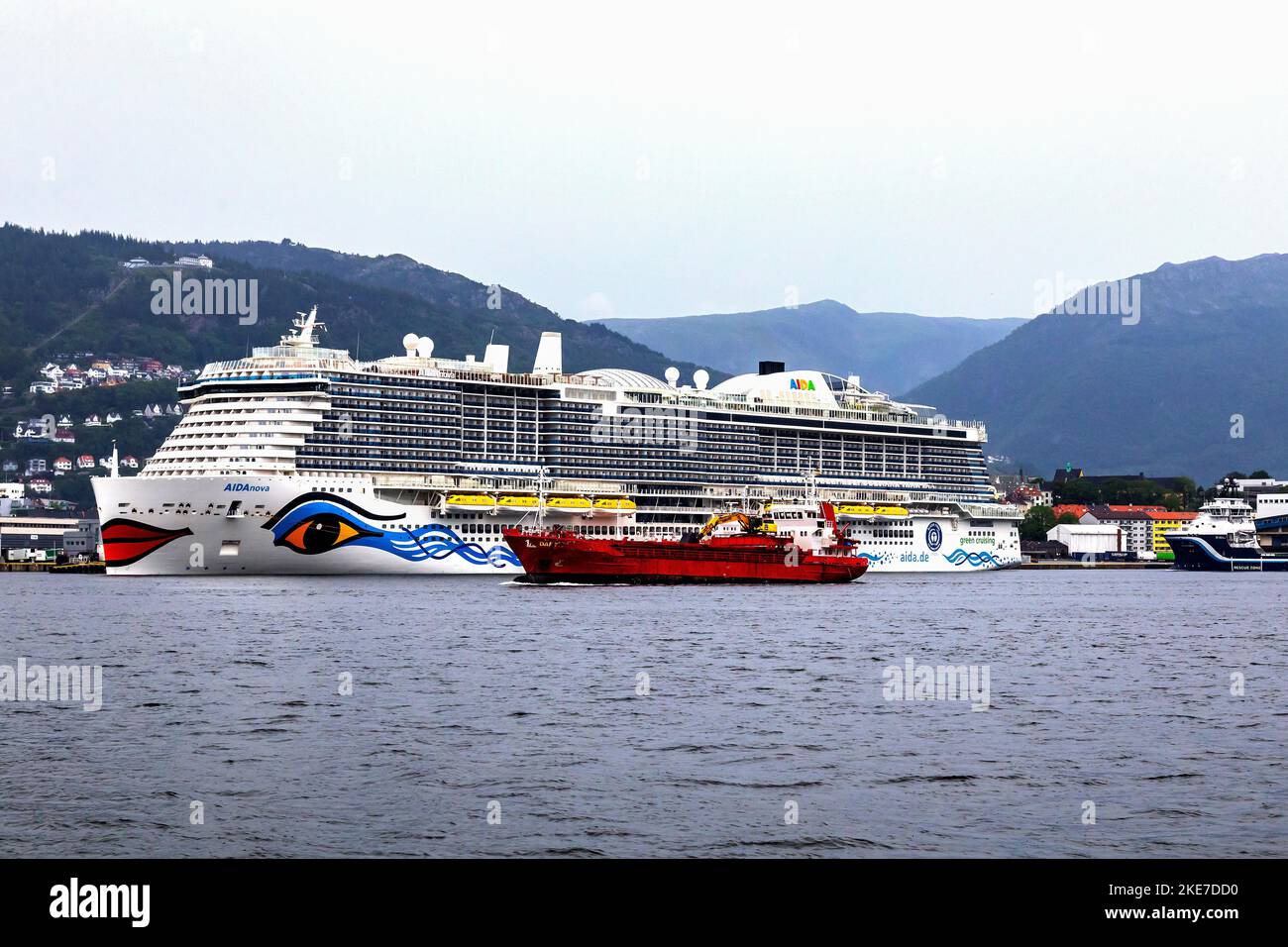 Kreuzfahrt-Schiff Sky AIDAnova am Jekteviken Terminal im Hafen von Bergen, Norwegen. Vorbereitung auf die Abfahrt. Altes Stückgutfrachter Dantic, das vorbeifährt Stockfoto