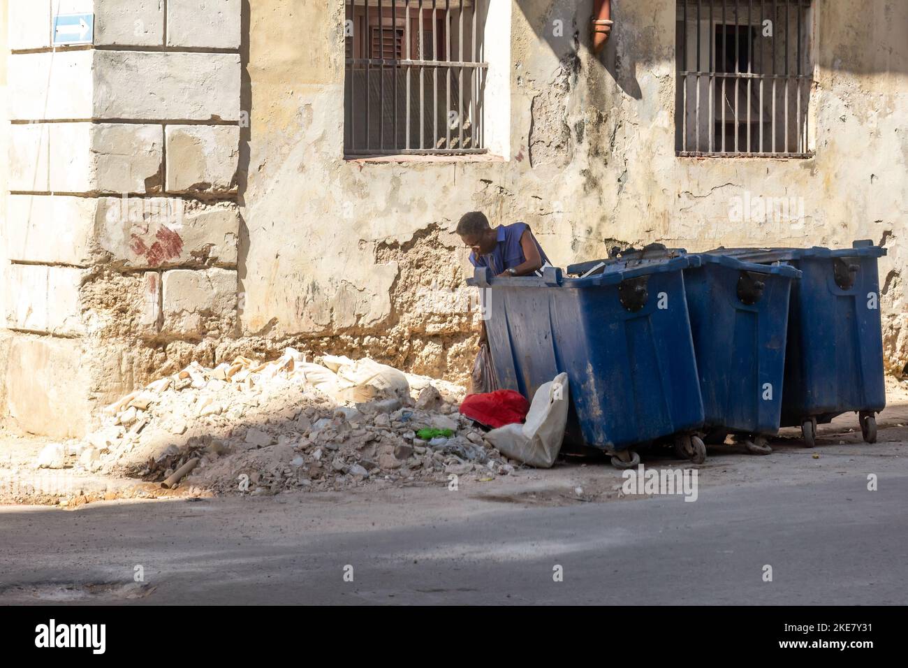 Ein Kubaner wirft Bauschutt in einem Stapel von beschädigten städtischen Mülltonnen ab Stockfoto