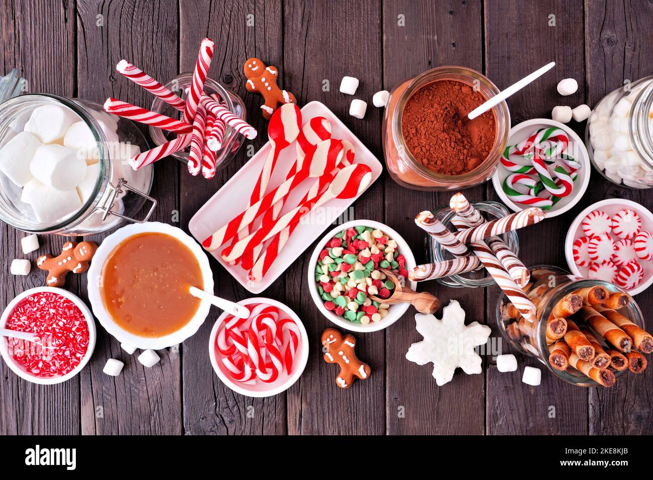 Weihnachts-Tafel mit heißer Schokolade und einer Mischung aus süßen Belägen. Draufsicht Tischszene auf dunklem Holzhintergrund. Stockfoto