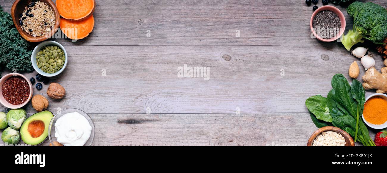 Gesunde Lebensmittelzutaten. Draufsicht doppelseitiger Rand auf einem Holzbanner Hintergrund. Speicherplatz kopieren. Super-Food-Konzept mit grünem Gemüse, Beeren, whol Stockfoto