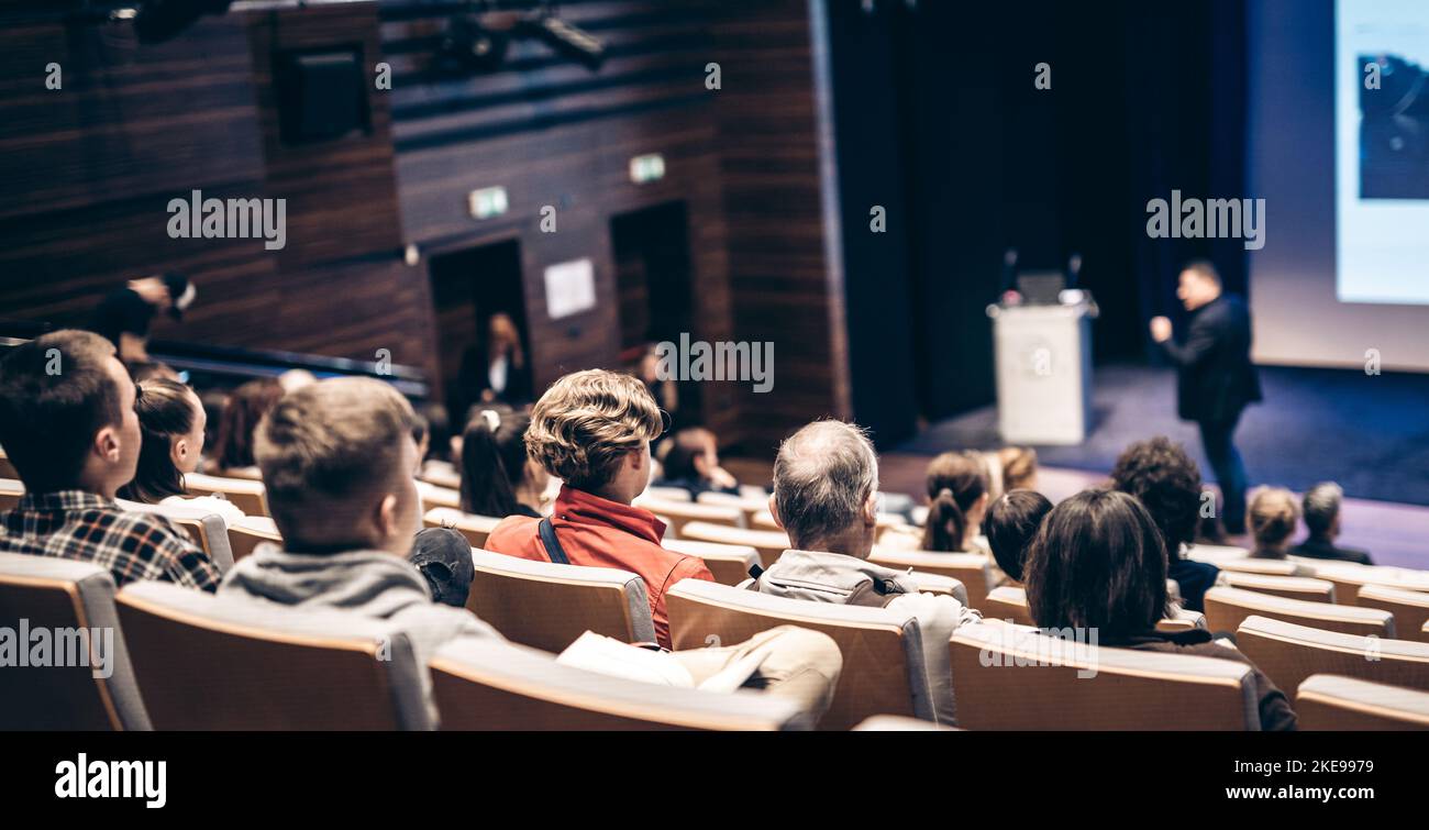 Referent, der bei einer Geschäftsveranstaltung im Konferenzsaal spricht. Rückansicht von nicht erkennbaren Personen im Konferenzsaal. Business und Entrepreneurship Konzept Stockfoto