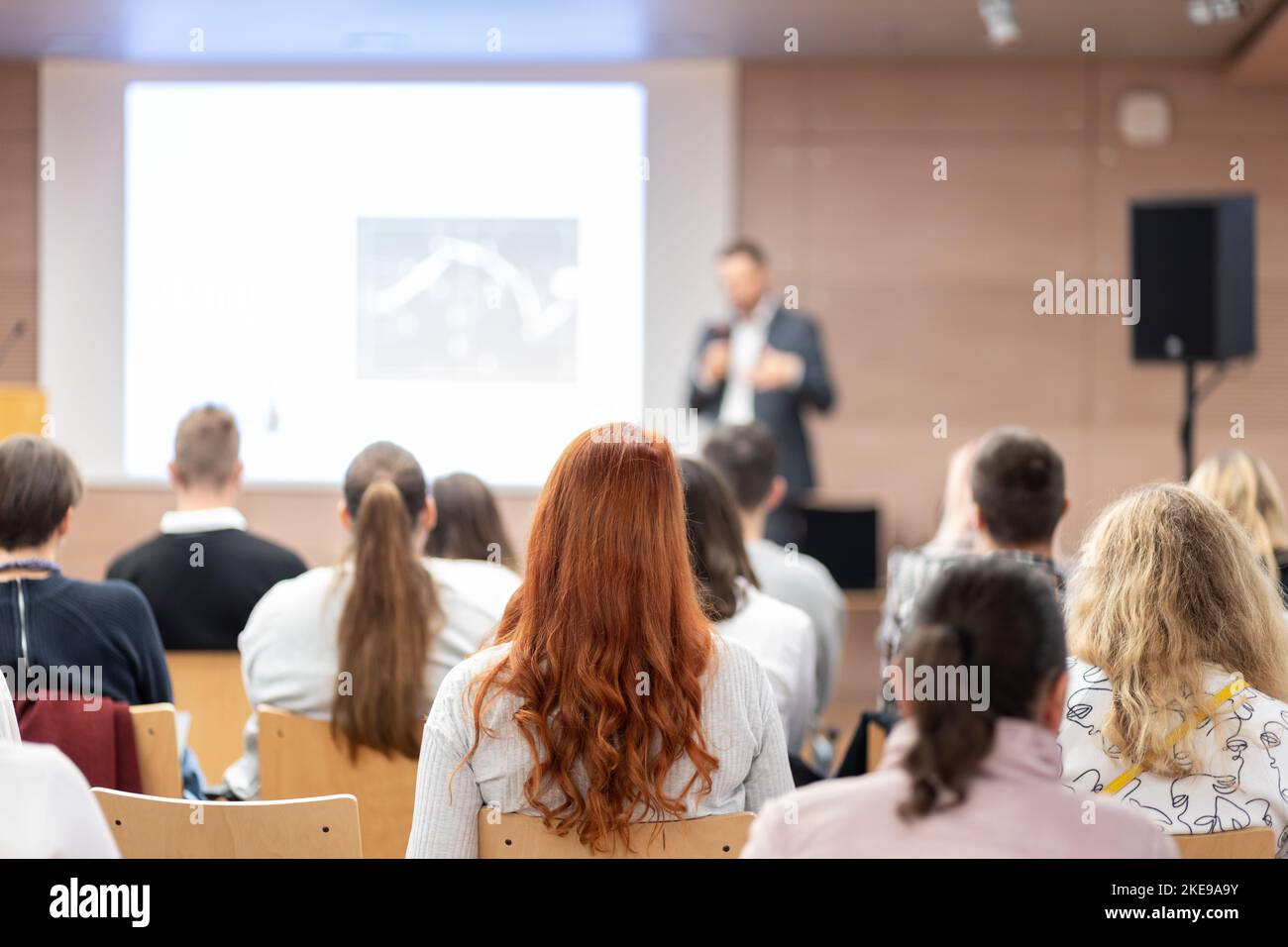 Referent, der bei einer Geschäftsveranstaltung im Konferenzsaal spricht. Rückansicht von nicht erkennbaren Personen im Konferenzsaal. Business und Entrepreneurship Konzept Stockfoto