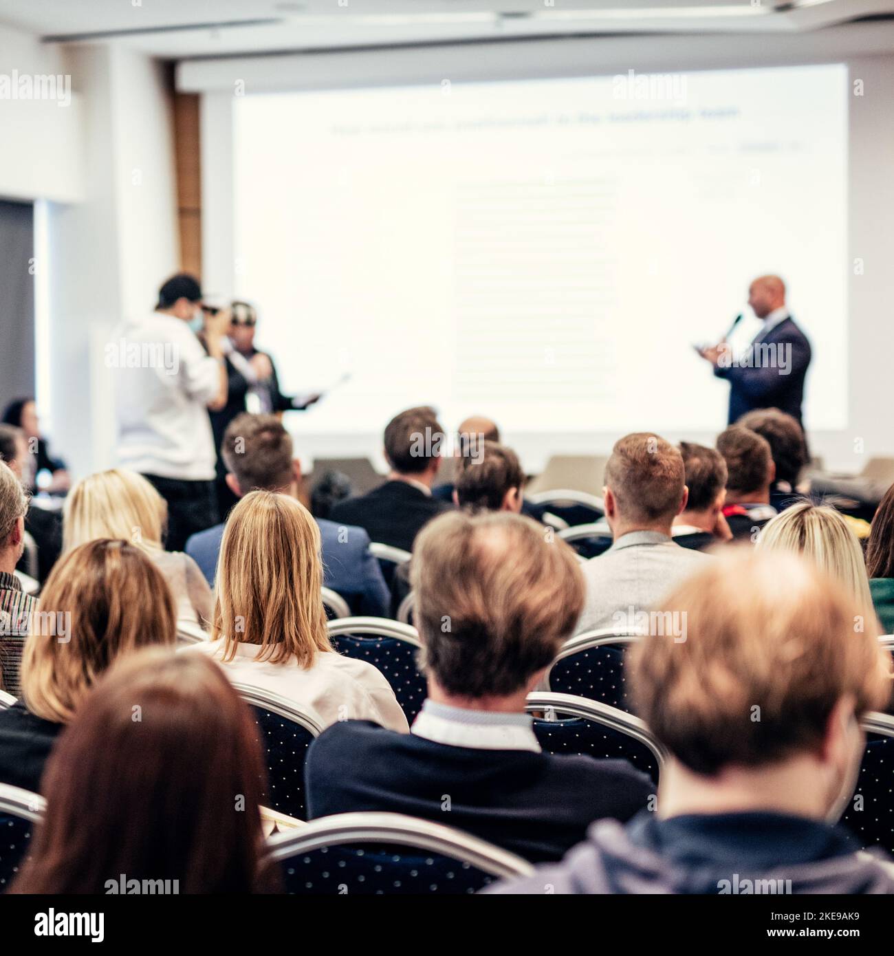 Ich habe eine Frage. Gruppe von Geschäftsleuten, die an den Stühlen im Konferenzsaal sitzen. Geschäftsmann steht auf und stellt eine Frage. Konferenz und Präsentation. Unternehmen und Unternehmertum. Stockfoto