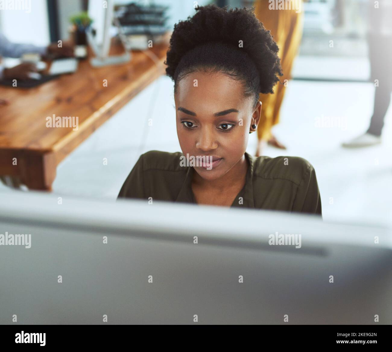 Schneller Lösungen finden mit Technologie. Eine junge Geschäftsfrau, die in einem modernen Büro an einem Computer arbeitet. Stockfoto