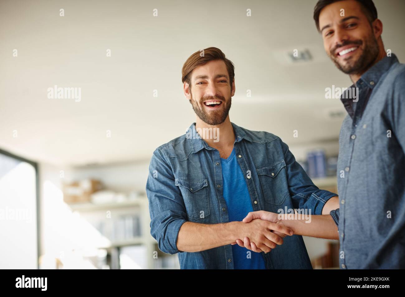Gemeinsam machen wir es möglich. Porträt von zwei Geschäftsleuten, die sich im Büro die Hände schütteln. Stockfoto