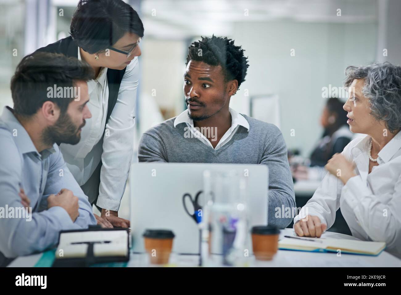 Eine Gruppe von Kollegen, die in einem modernen Büro gemeinsam auf einem Laptop Brainstorming durchführen. Stockfoto