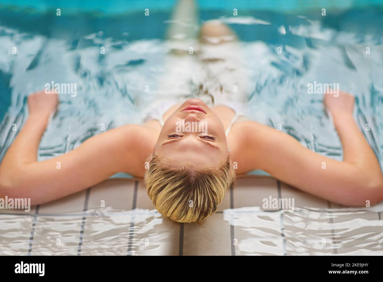 Sparen Sie sich einen Tag für etwas Entspannung. Rückansicht einer jungen Frau, die sich in einem Spa im Pool entspannen kann. Stockfoto