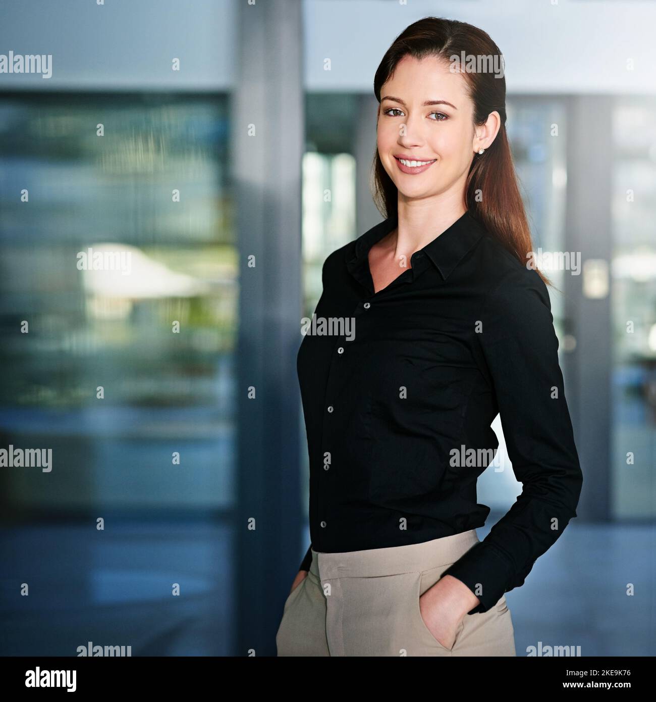 Der Erfolg ist sicher. Porträt einer jungen Geschäftsfrau, die mit den Händen in den Taschen im Büro steht. Stockfoto