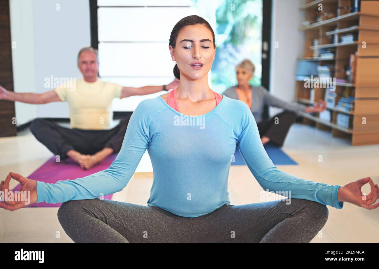 Befreien Sie Ihren Körper von jeglicher Spannung. Ein Yoga-Lehrer führt ein Seniorenpaar in einem Yoga-Kurs. Stockfoto