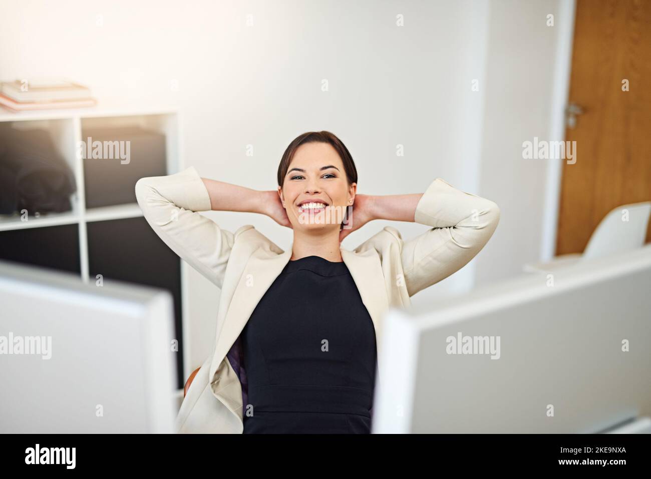 Erfolg fühlt sich sicher gut an. Eine glückliche Geschäftsfrau, die sich an ihrem Schreibtisch entspannt. Stockfoto