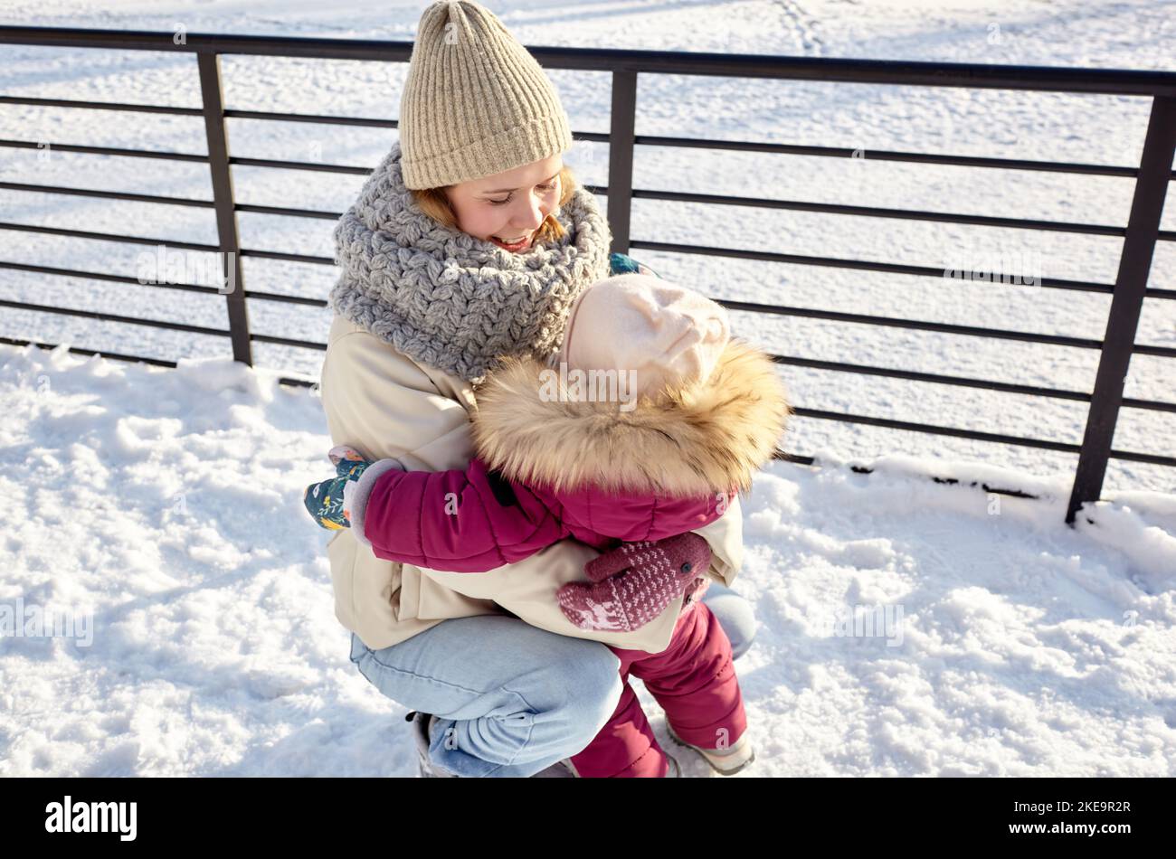 Mutter und Tochter gehen an Weihnachten und Neujahr im winterlichen Stadtpark spazieren. Eltern und kleine Kinder haben Spaß im Freien Stockfoto
