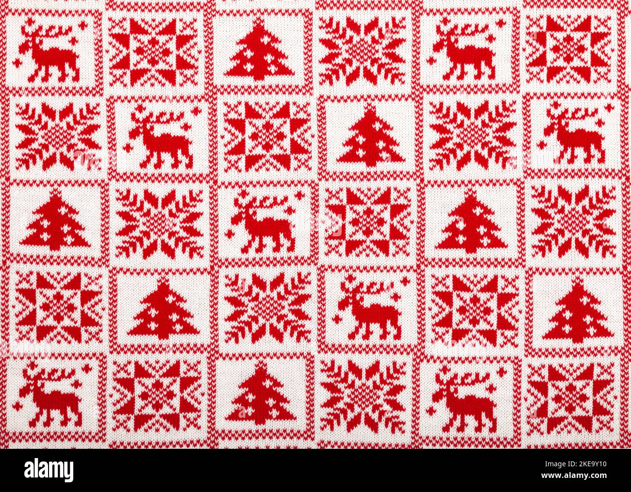 Roter Strickstoff mit weißem Elch, Tanne und Schneeflocke skandinavischen Stil geometrische Ornament Cristmas Hintergrund Stockfoto