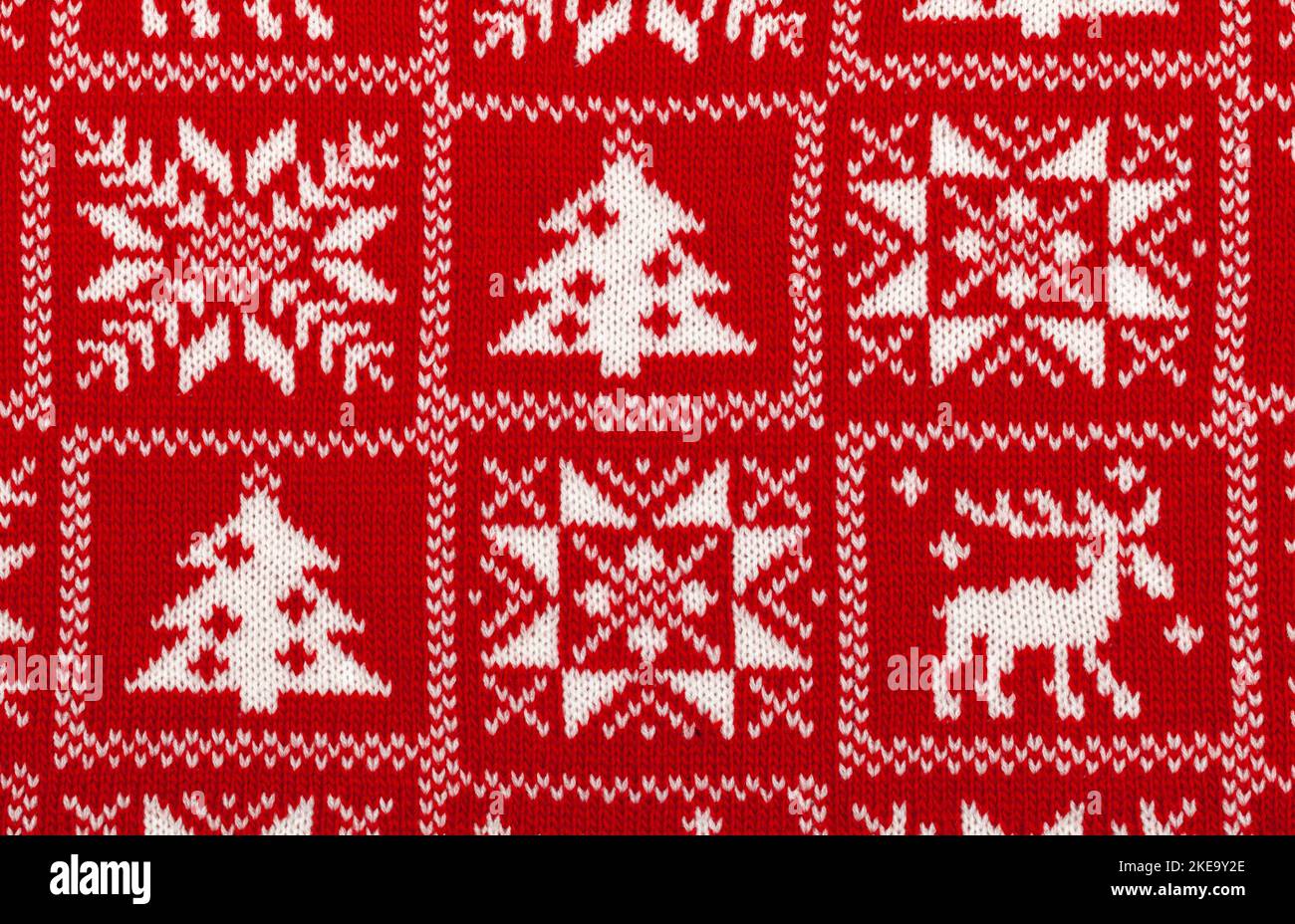 Roter Strickstoff mit weißem Elch, Tanne und Schneeflocke skandinavischen Stil geometrische Ornament Cristmas Hintergrund Stockfoto