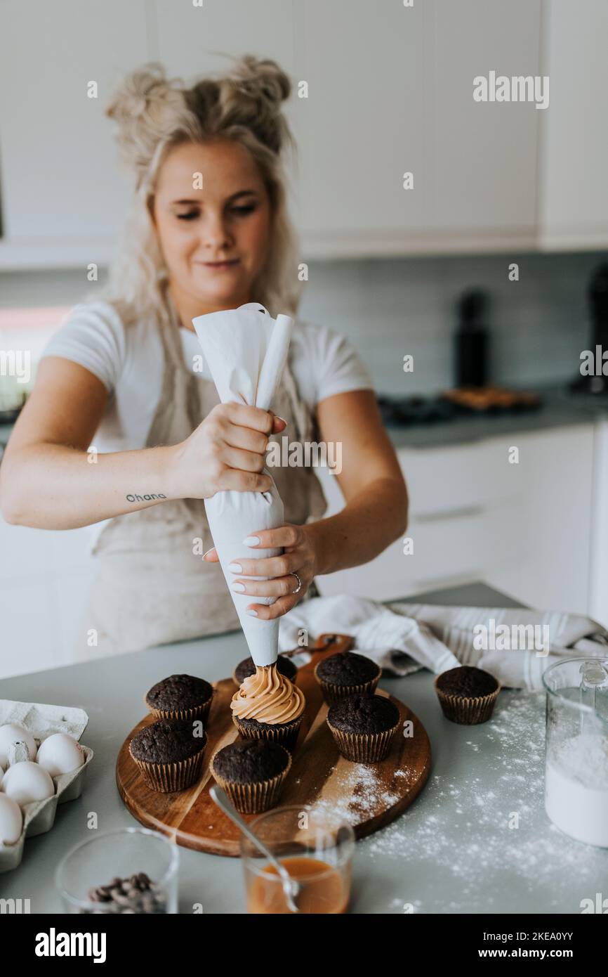 Frau, die Cupcakes mit Eis bestäube Stockfoto