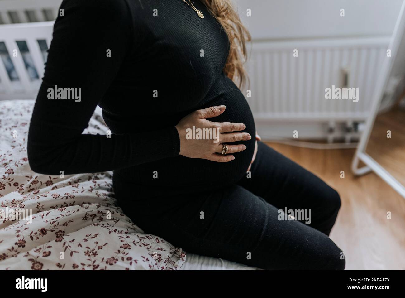Eine Schwangerin sitzt auf dem Bett und berührt den Bauch Stockfoto