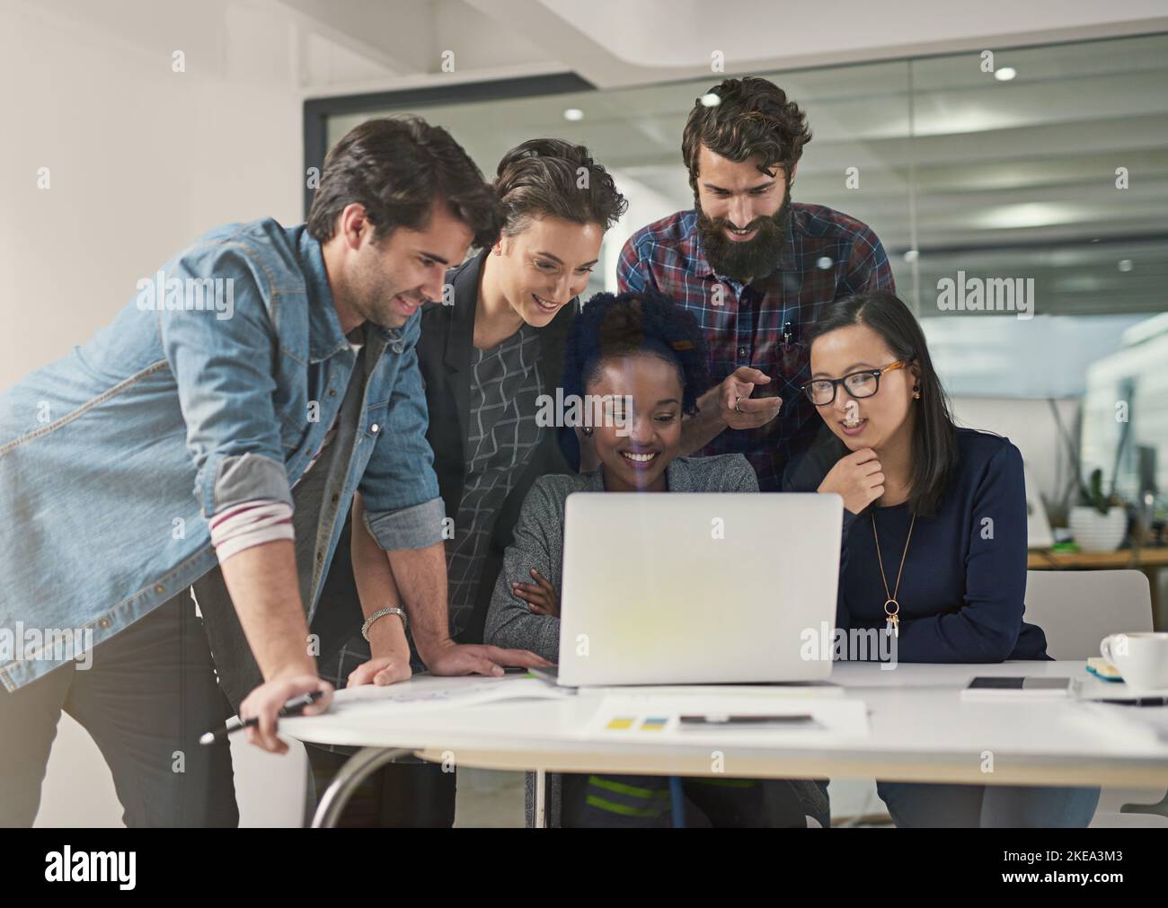 Ihre unterschiedlichen Beiträge helfen ihnen, die Dinge anders zu betrachten. Eine Gruppe von Designern, die sich zusammentrat, um sich etwas auf einem Laptop anzusehen. Stockfoto