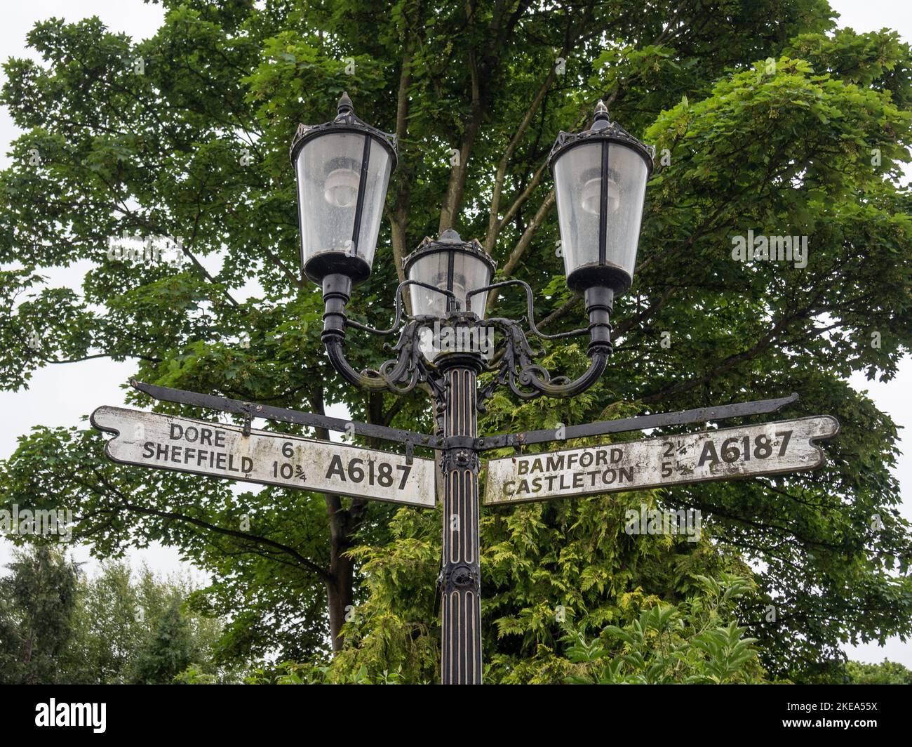 Altmodische Metalllampe mit drei Leuchten, die auch Fingerpost-Straßenschilder enthalten, Hathersage, Derbyshire, Großbritannien Stockfoto