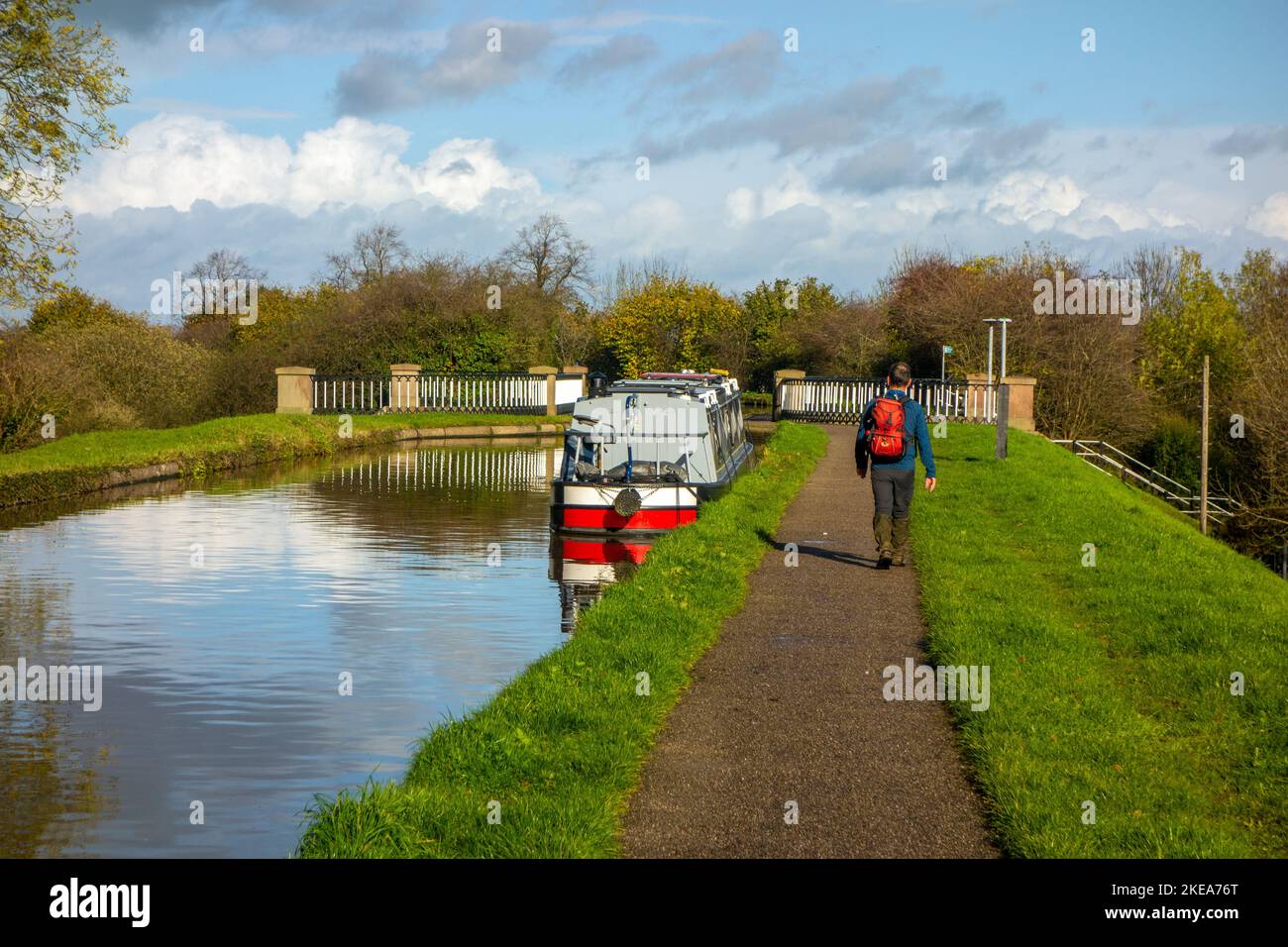 Mann, der am Shropshire Union Kanal bei Nantwich Cheshire entlang des Kanalpfades in Richtung des von Thomas Telford entworfenen Aquädukts an Schmalbooten vorbeiläuft Stockfoto
