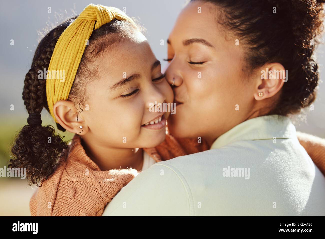 Mutter, Kind und Kuss mit einem Lächeln für Umarmung, Liebe oder Pflege in der Familie Bindung, Reisen oder Sommerferien im Freien. Mama hält und küsst Tochter Stockfoto
