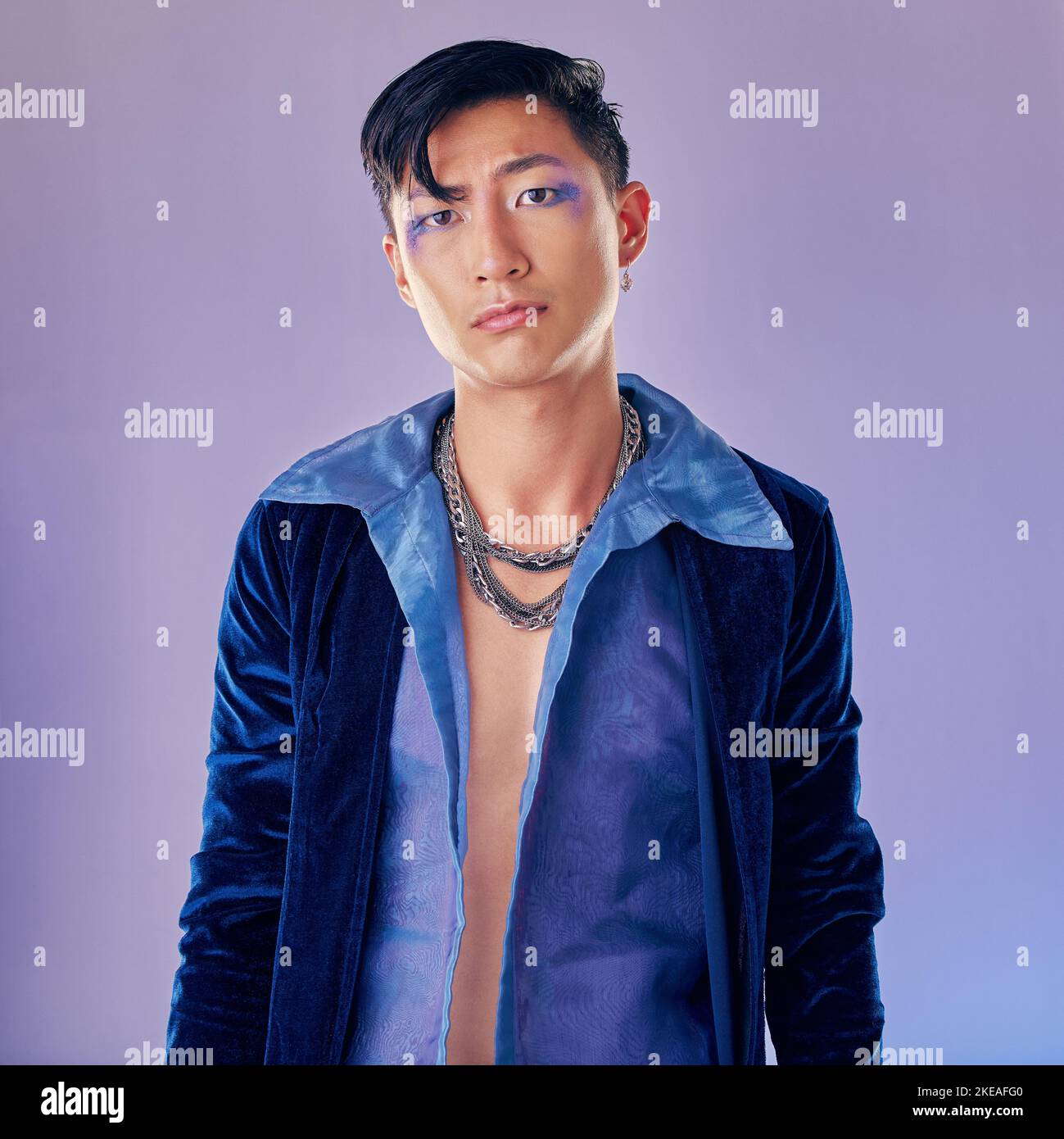 Asiatischer Mann, Make-up und Punk Mode für Portrait im Studio mit Cyberpunk, kreativem oder ästhetischem Gesicht. Futuristisches Modell, Metallschmuck oder Kleidung Stockfoto