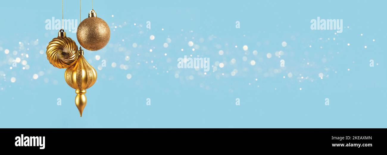 Weihnachtsbanner mit drei goldenen Kugeln Dekorationen auf blauem Hintergrund mit Bokeh-Lichtern mit Kopierraum. Weitwinkelvorsatz Stockfoto