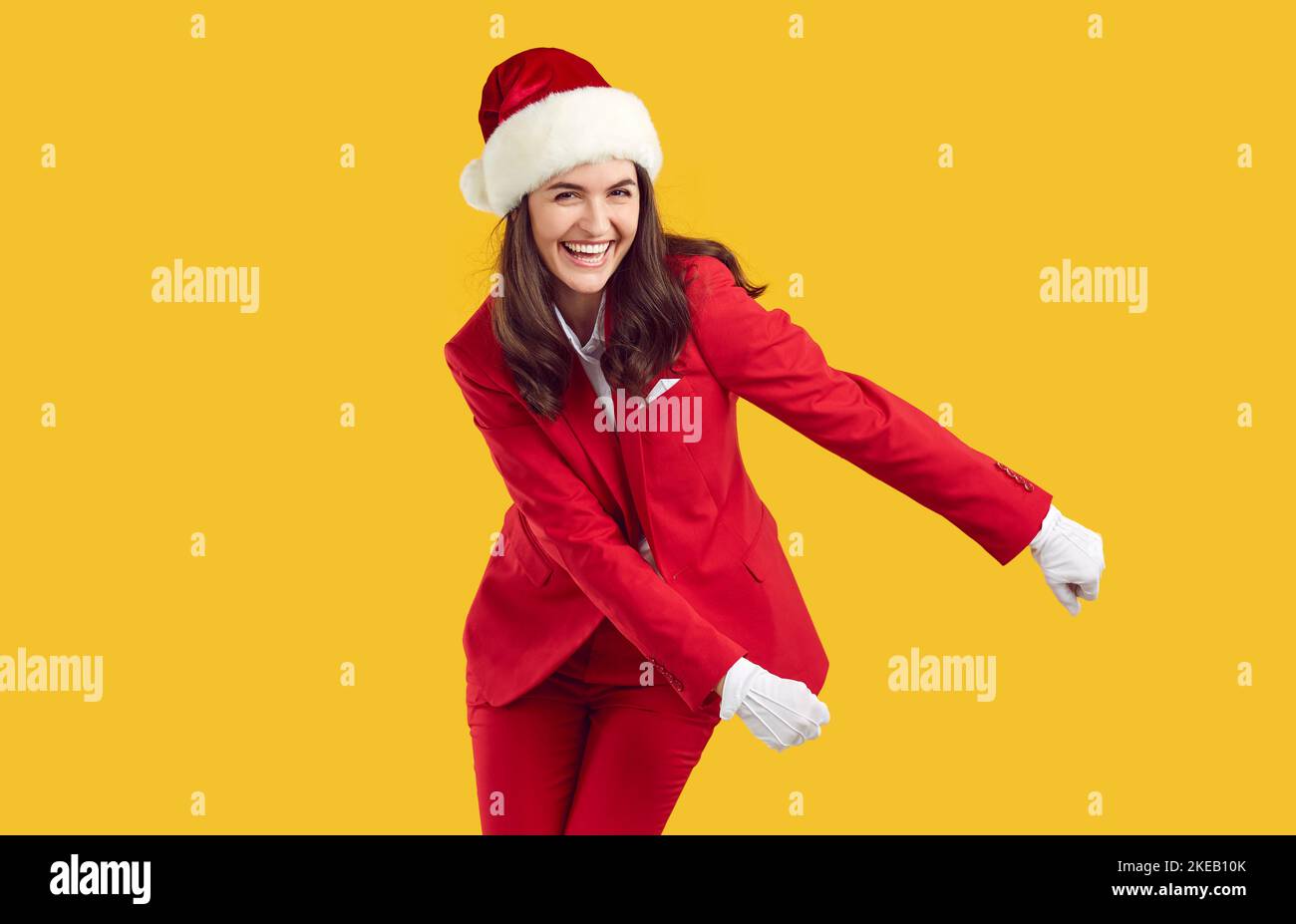 Lachende fröhliche Frau trägt Santa-Stil tanzen swish Rucksack Tanz auf gelbem Hintergrund. Stockfoto