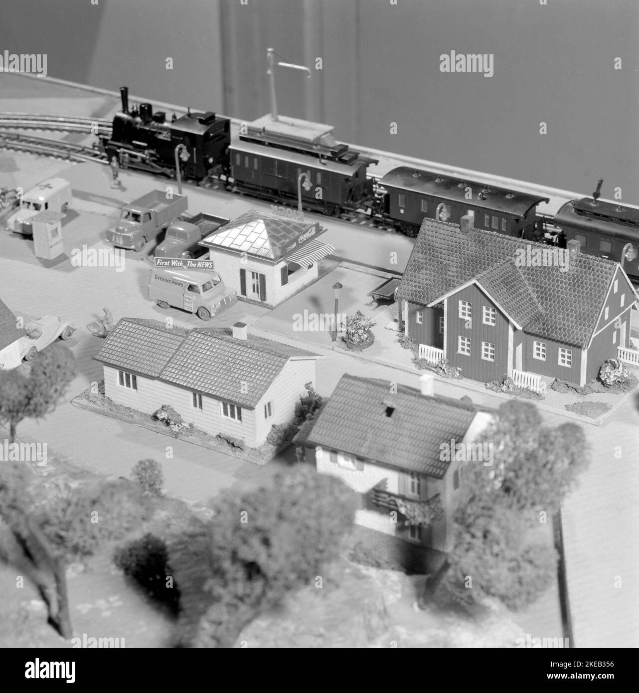 In der 1950s. Eine Modelleisenbahn, die auf einem Tisch in einem Kinderzimmer montiert ist. Die Modelleisenbahn hat Häuser, Bäume, Tiere und Menschen in ihr als maßstabsgetrete Modelle. Höchstwahrscheinlich ein Zugsatz des deutschen Herstellers Fleischmann, da die Schienen das typische zweigleisige Gleichstrom-System sind. Ein maßstabsgezeichtes Modell eines abendlichen Nachrichtenwagens mit einem Schild auf der Oberseite, das zuerst mit den Nachrichten sagte. Schweden 1958. Conard Ref. 3867 Stockfoto