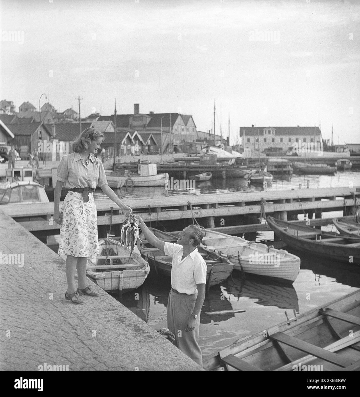 In der 1940s. Eine Szene, die während der Dreharbeiten zu einem Film in Bohuslän Schweden aufgenommen wurde. Sie schüchtern Fischer gespielt von Olle Tärna gibt dem Mädchen seiner Träume Fisch. Eine Art Balz, die zu einer Romanze geführt haben könnte. Schweden 1947. Kristoffersson AD1-10 Stockfoto