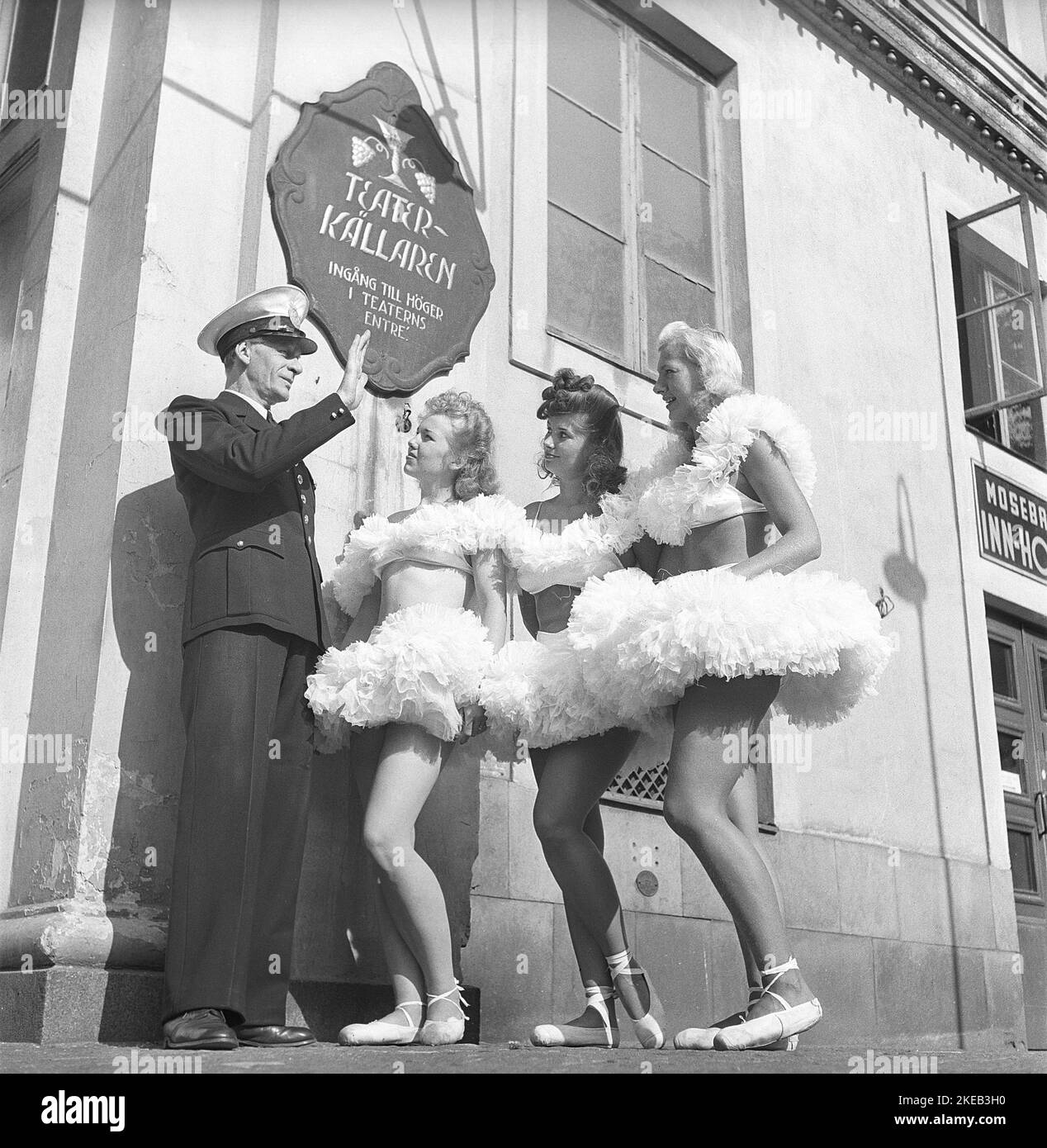 In der 1940s. Drei Mädchen in Ballettkleidung stehen vor einem Establishment, vor dem ein uniformierte Mann steht, der seinen Arm als Stoppschild hochhält. Warum den drei Mädchen entsagt wird, ist unbekannt. Schweden 1947 Kristoffersson Ref AD40-4 Stockfoto