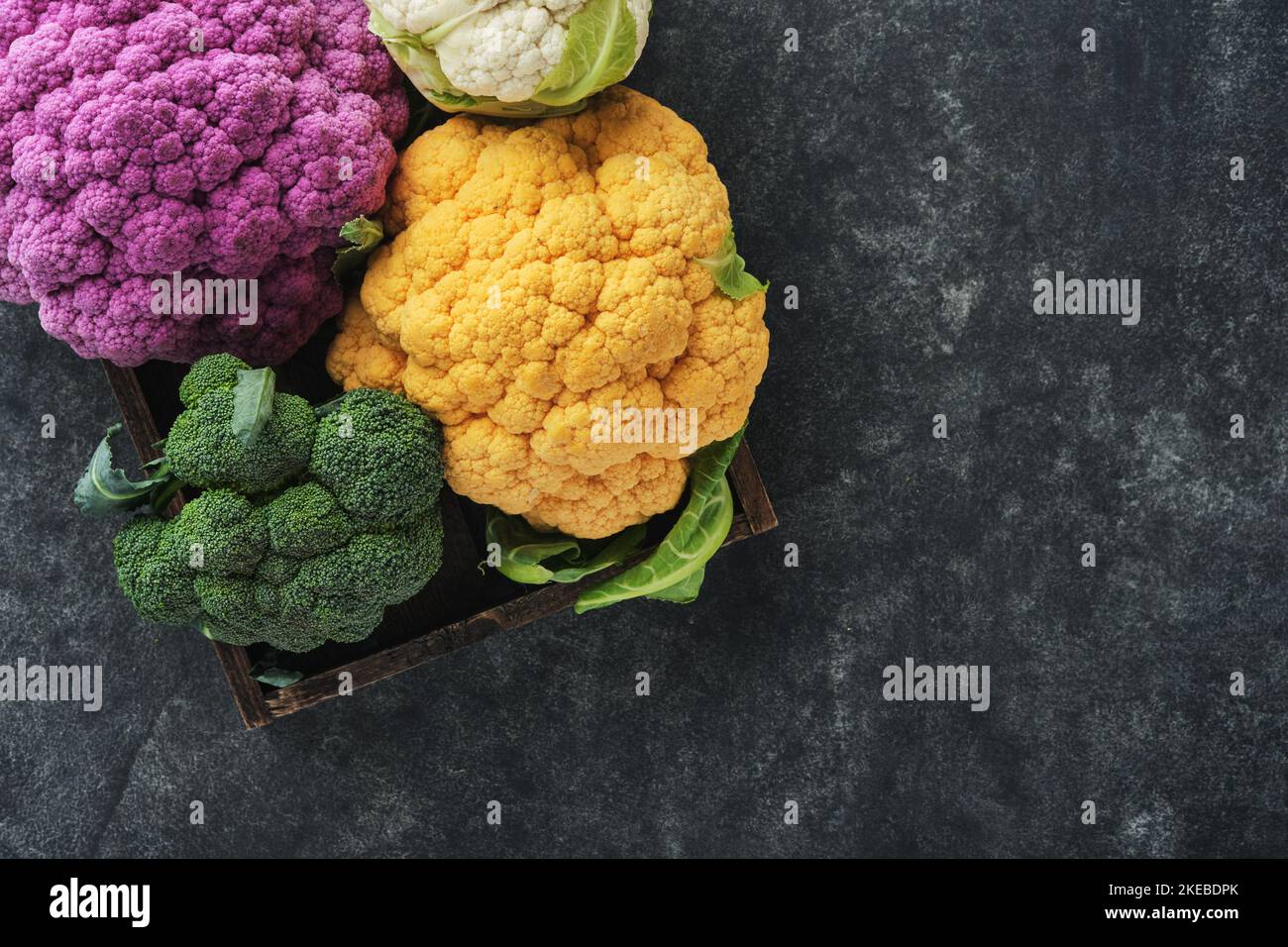 Colorfu-Blumenkohl. Verschiedene Blumenkohl auf altem dunkelgrauen Betonhintergrund. Violette, gelbe, weiße und grüne Farbkabbage. Brokkoli und Ro Stockfoto