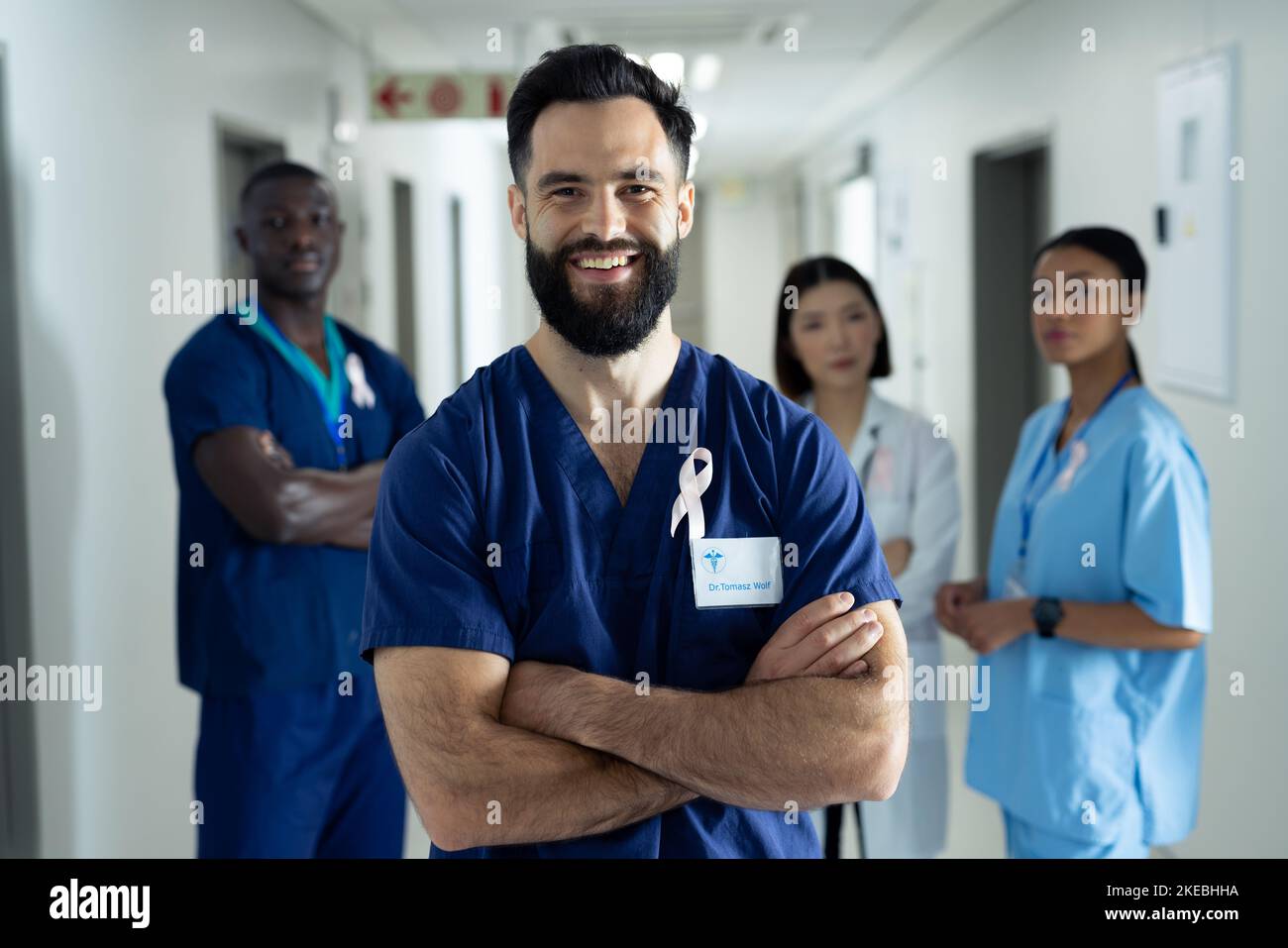 Porträt eines lächelnden Kaukasier-Gesundheitsdienstleisters mit Krebsband im belebten Krankenhausgang Stockfoto