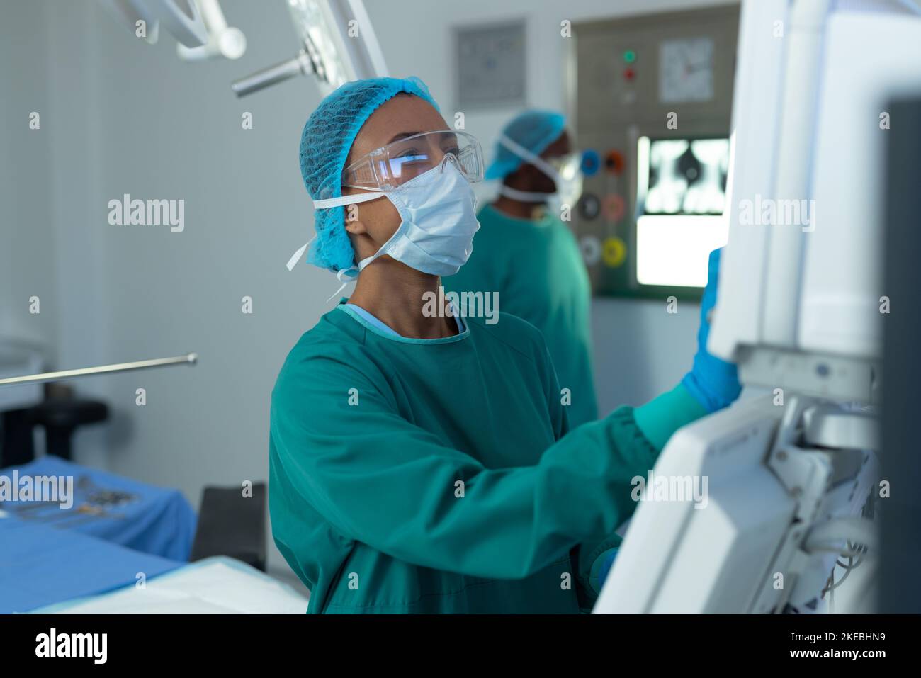Birassische Chirurgin, die computergestützte medizinische Geräte im Operationssaal betreibt Stockfoto