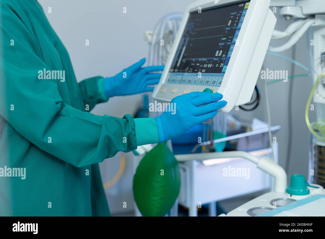 Die Mittelschicht der Handschuhe des Chirurgen, die computergestützte medizinische Geräte im Operationssaal bedienen Stockfoto
