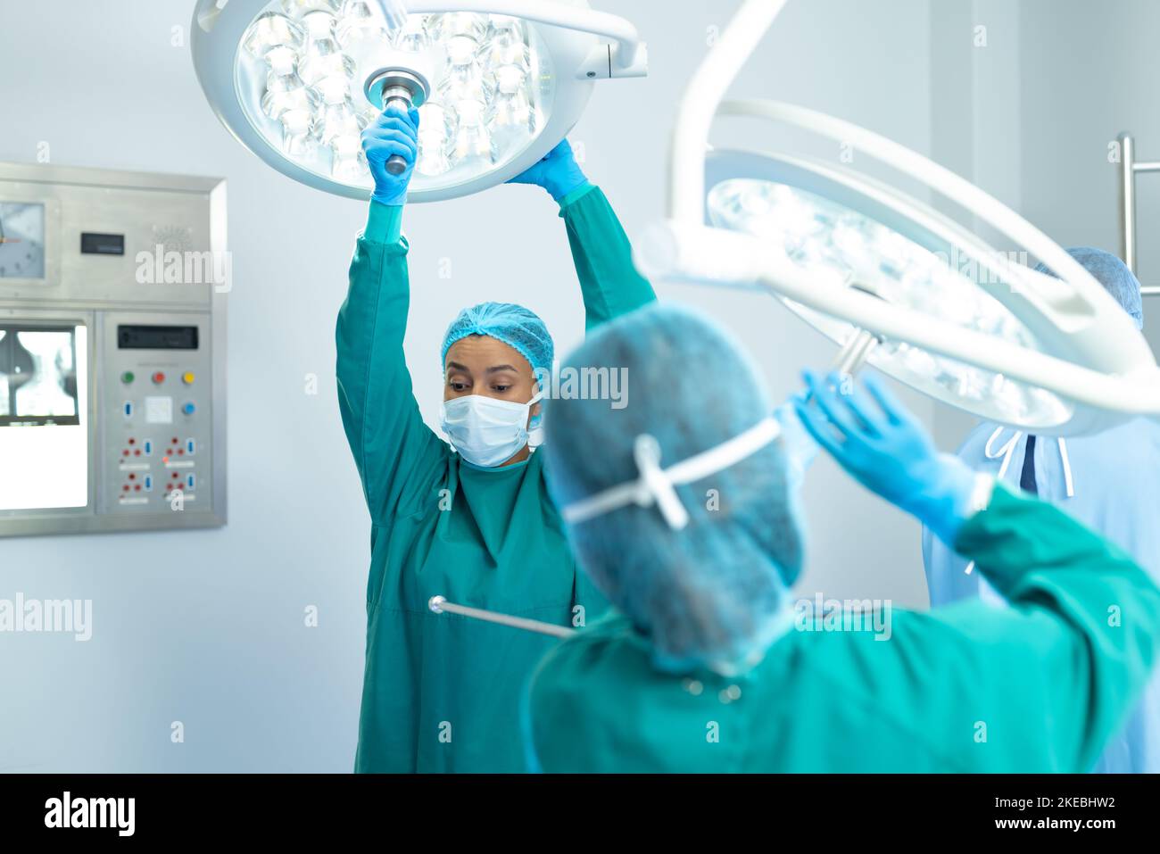 Birassische Chirurgin und Kollegin, die die Lichter im Operationssaal für die Operation justiert Stockfoto