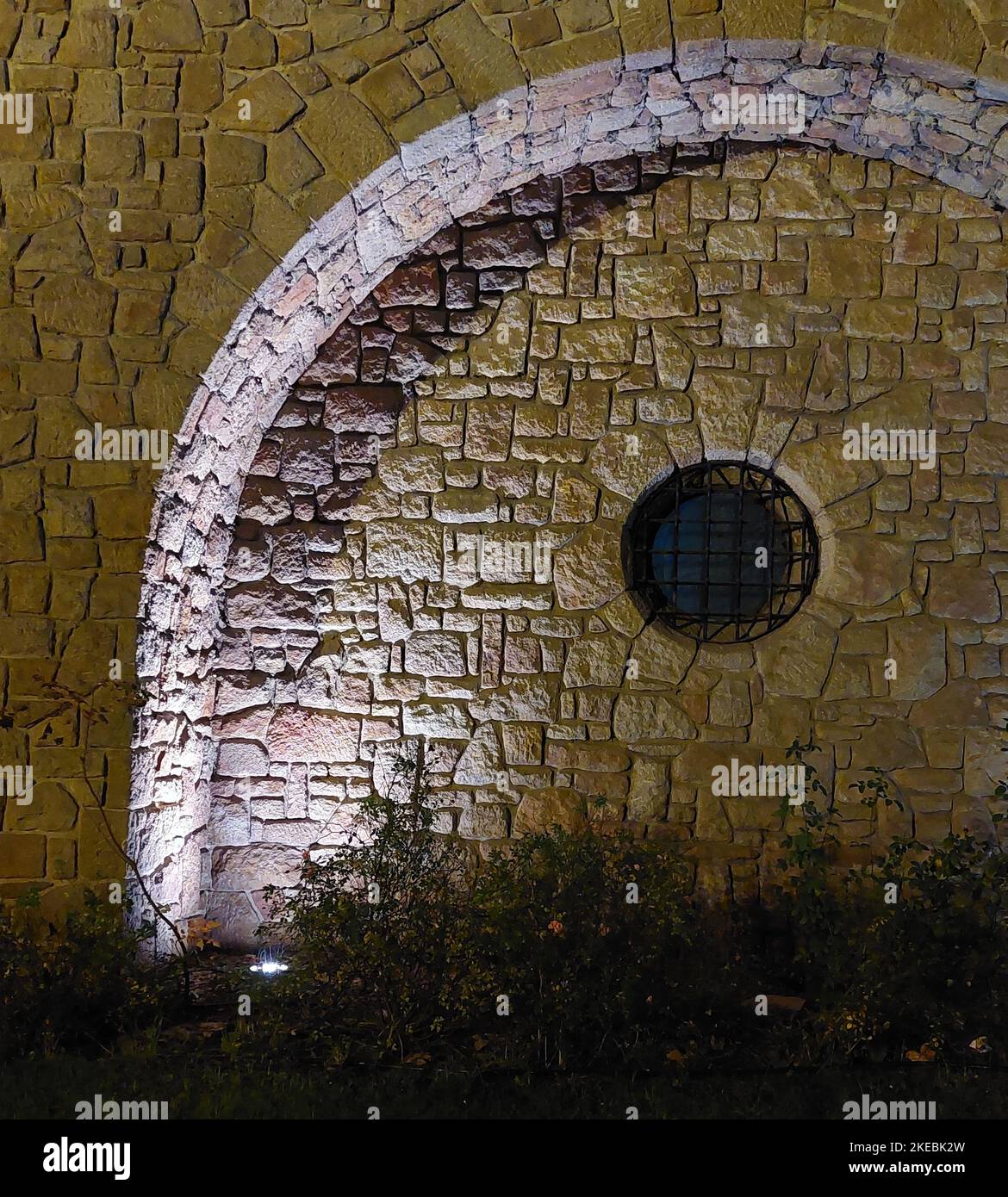 Rundes Fenster mit steinerner Wandgewölbe. Abendbeleuchtung Stockfoto
