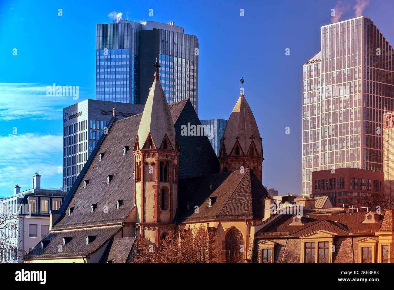 Frankfurt, 30. Dezember 2019: Eine mittelalterliche Kirche und die modernen Glastürme des Bankenviertels stehen in Frankfurt im harten Kontrast Stockfoto