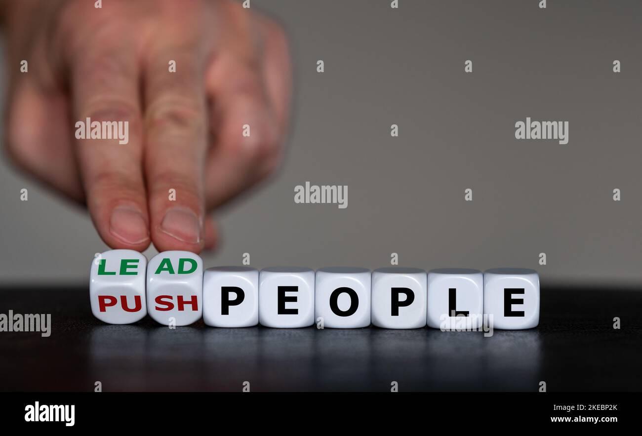 Die Hand dreht Würfel und ändert den Ausdruck „Push peapple“ in „Lead people“. Symbol für eine kompetente Führung. Stockfoto