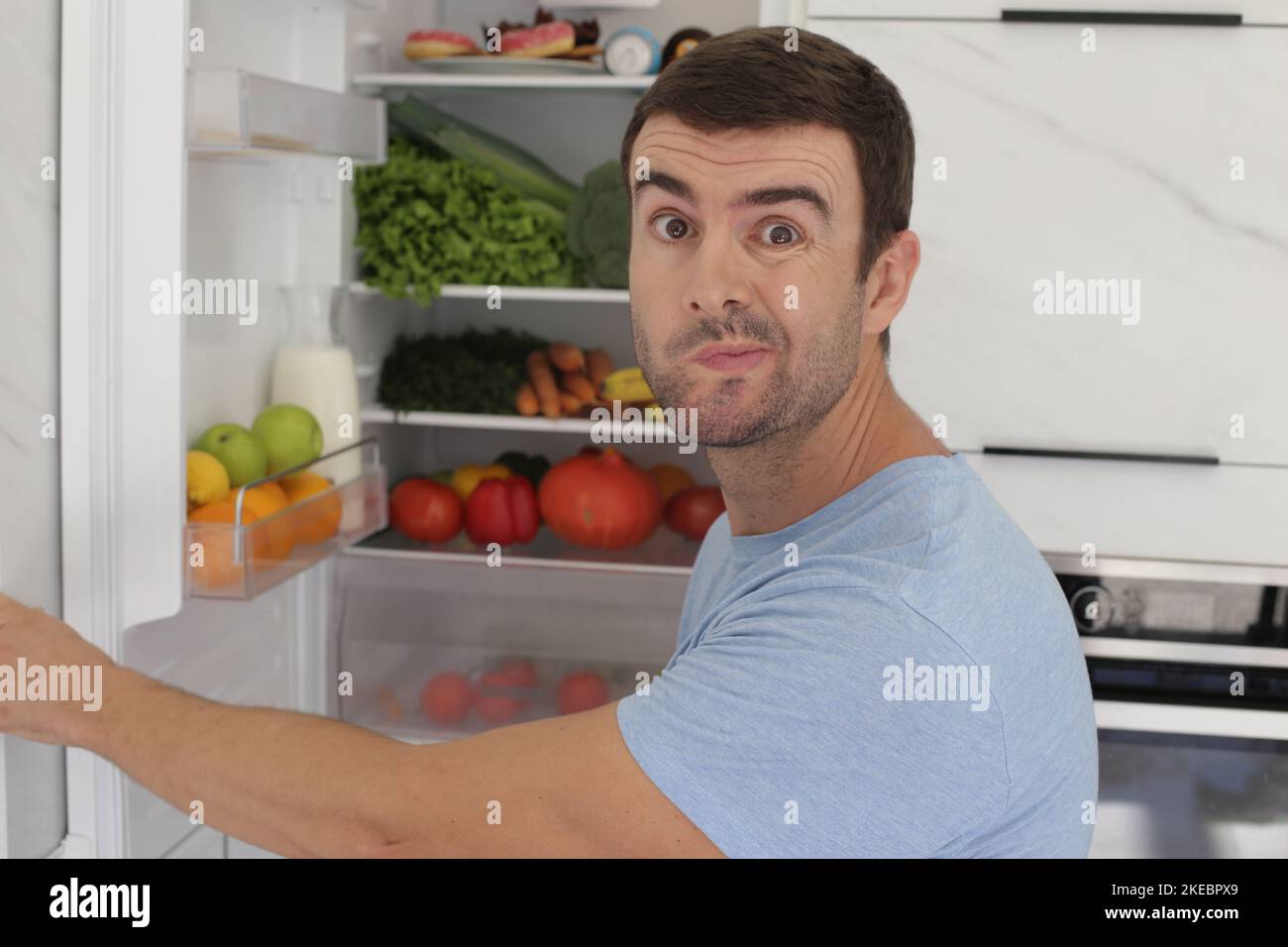 Ein Mann öffnet die Kühlschranktür mit Zweifeln Stockfoto