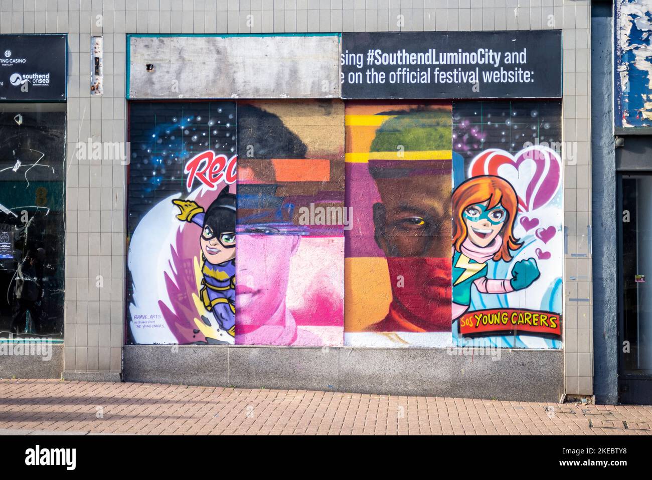 Verfallende Schichten von Kunstwerken und Werbung auf dem Horten eines geschlossenen High Street-Shops in Southend on Sea, Essex. Marcus Rashford unter Cartoons Stockfoto