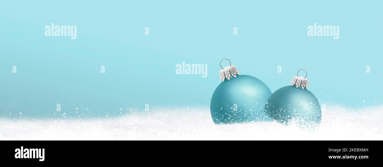 Verschneite Weihnachtskugeln vor blauem Hintergrund Stockfoto