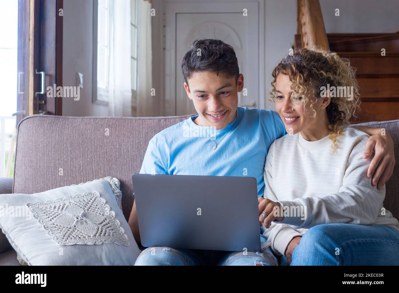 Erwachsener Sohn und Mutter im mittleren Alter von 40s Jahren sitzen auf der Couch im gemütlichen Wohnzimmer mit einem Notebook auf dem Schoß und lachen über einen lustigen Comedy-Film, genießen Sie Online-Unterhaltungsangebote auf Websites, virtuelles Online-Spaßkonzept im Internet Stockfoto