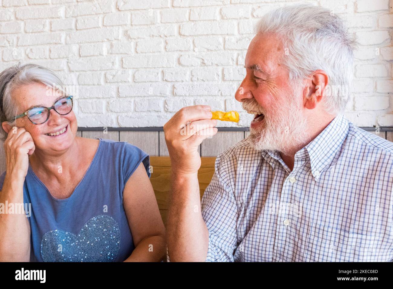 Paar und Porträt von zwei glücklich reifen Menschen Senior Essen In einem Fast Food oder Restaurant zusammen lächeln und haben Spaß Lachen - glücklich und niedlich Lebensstil und Konzept Zwei Rentner zu Hause Stockfoto